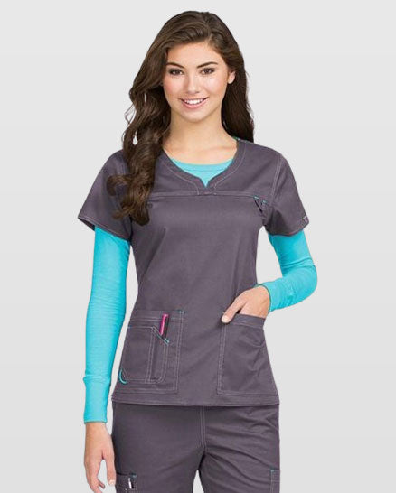 A woman is wearing a gray Med Couture 'MC' Lexi Top Scrub Top with a teal undershirt and gray scrub pants.